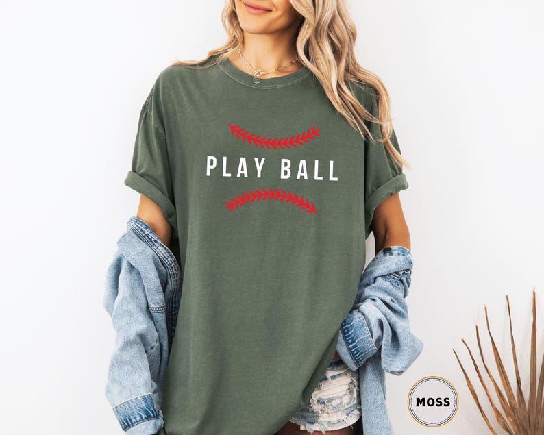 May include: A green t-shirt with a white graphic that says "Play Ball" with red stitching around the text.