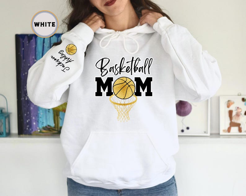 May include: White hoodie with a basketball and the text "Basketball Mom" printed on the front. The hoodie has a drawstring hood and a kangaroo pocket.