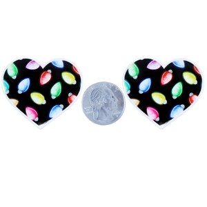 May include: Two heart-shaped earrings with a black background and colorful Christmas light bulbs. A quarter is placed between the earrings for size comparison. The earrings have a white border.