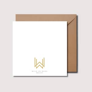 Pu&ograve; includere: Un biglietto di auguri bianco vuoto con una busta marrone. Il biglietto ha un logo dorato che dice "Whisk and Whirl Designs" con una "W" stilizzata al centro.