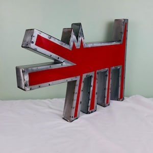 May include: A large, metal sculpture in the shape of a stylized dog. The sculpture features a red interior with a silver metal frame. The dog's head and body are clearly defined, with a unique, artistic design. The sculpture is placed on a white surface.