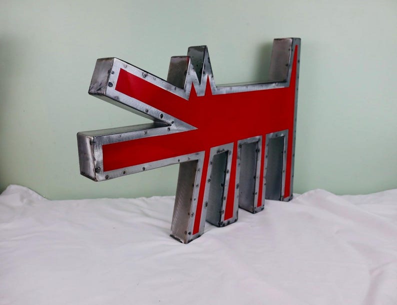 May include: A large, metal sculpture in the shape of a stylized dog. The sculpture features a red interior with a silver metal frame. The dog's head and body are clearly defined, with a unique, artistic design. The sculpture is placed on a white surface.