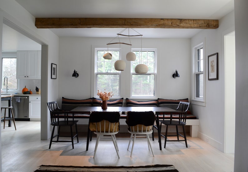 The Boomerang XL hangs from an exposed wooden beam, offering a lovely compliment to the curved wood featured in the chandelier's sculptural design. In the daylight, the matte white shades are tempted to blend in, but the curves command attention.