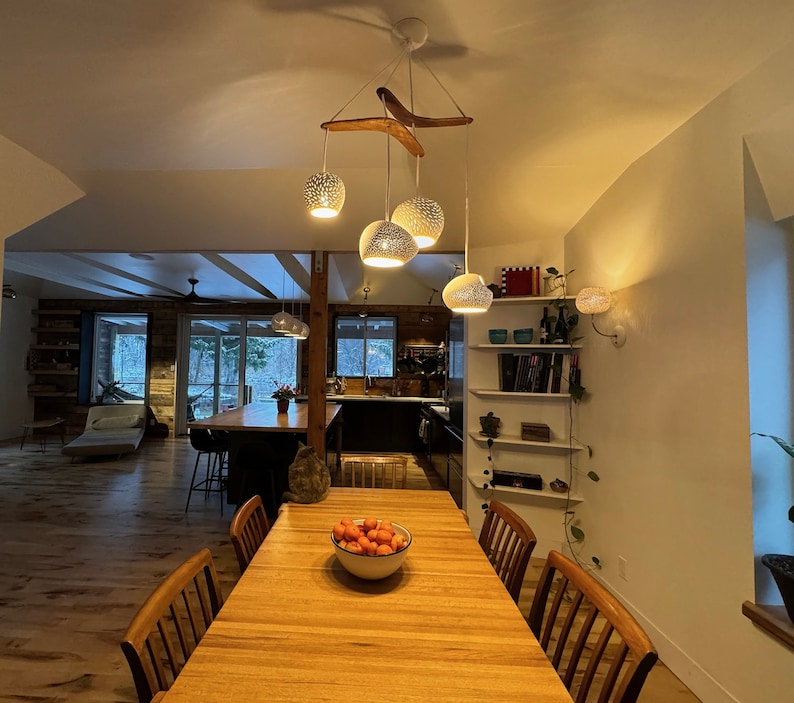 The boomerang large hangs above a clean wood dining room table in an open concept home. The visual interest of the fixture provides a focal point, and plenty of light.