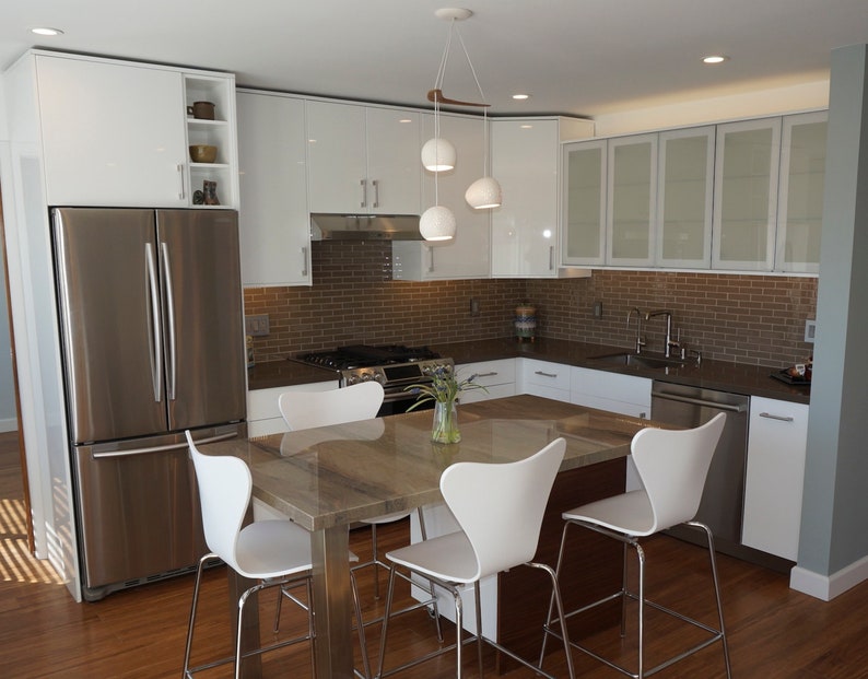 A sleek new kitchen features the Boomerang 3 above a veined stone island surrounded in white moulded counter stools.