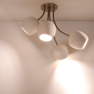May include: A white ceiling light fixture with five curved arms and four round white light bulbs.