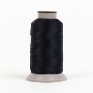 May include: A spool of black thread on a white plastic bobbin.