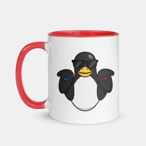 May include: A white ceramic mug with a red rim and handle. The mug features a cartoon penguin wearing sunglasses and holding a blue and red object in each hand.