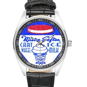 May include: A silver wristwatch with a black leather band. The watch face features a blue and white design with the words "Mister Softee" and "Cart Ice Milk Wheel". The watch has a silver bezel and a black leather strap.