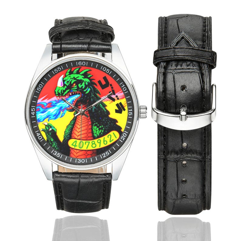 May include: A wristwatch with a silver case and a black crocodile-textured leather strap. The watch face features a green monster breathing blue fire against a red and yellow background, with the text 40789621 and Japanese characters printed.
