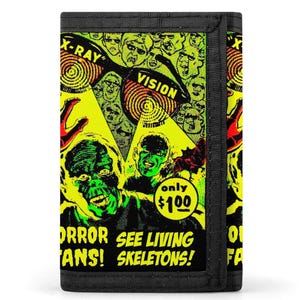 May include: A black tri-fold wallet featuring a vibrant yellow and green graphic print of a horror comic book cover. The design includes text reading X-RAY VISION, ORROR, SEE LIVING SKELETONS, and a circle graphic with the text only $100.