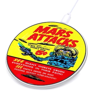 May include: A round wireless charger with a retro "Mars Attacks" design. The charger features a yellow background with red text and a cartoon alien illustration. Text includes "Space Adventure Bubble Gum" and "See Giant Insects Crush Everything".