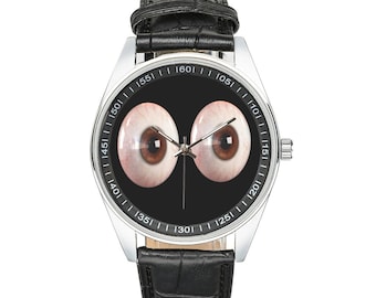 May include: A black leather wristwatch with a silver face and a design of two large eyes. The watch face has numbers around the edge.