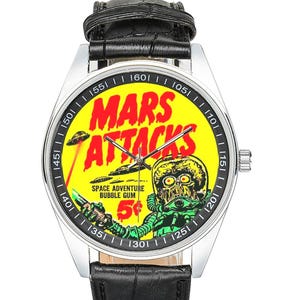 May include: A silver wristwatch with a black leather band. The watch face features a yellow background with the words "MARS ATTACKS" in red. A green alien graphic and the text "SPACE ADVENTURE BUBBLE GUM 5¢" are also visible.