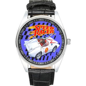 Può includere: Orologio da polso argentato con cinturino in pelle nera. Il quadrante dell'orologio presenta le parole "SPEED RACER" sopra un'auto da corsa bianca con il numero 5. Lo sfondo è blu con un motivo a scacchi.