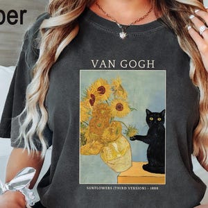 May include: Dark gray t-shirt featuring a print of Van Gogh's "Sunflowers (Third Version)" with a black cat. The text "VAN GOGH" is above the image, and "SUNFLOWERS (THIRD VERSION) - 1888" is below.