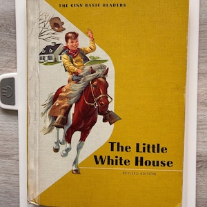 May include: Vintage children's book titled "The Little White House" with a yellow cover. The cover illustration depicts a young boy riding a brown horse. The book is part of "The Ginn Basic Readers" series.