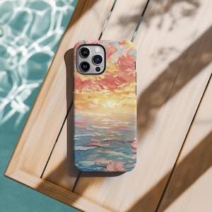 May include: A phone case with a painted design of a sunset over the ocean. The painting is done in shades of pink, orange, yellow, and blue. The case is made for an iPhone 13 Pro.