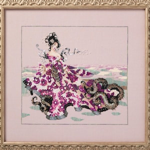 May include: Cross-stitch artwork of a woman in a floral gown with a long train. The dress is primarily white with large magenta flowers. The background is a light pink with a hint of a landscape. The artwork is framed in a gold-colored ornate frame.