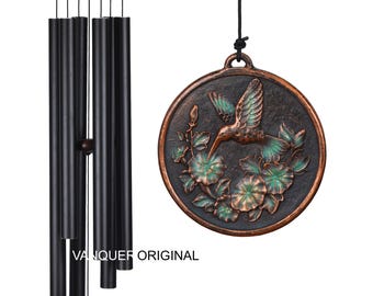 Könnte beinhalten: Ein schwarzer Windspiel mit einem dekorativen, bronzefarbenen Medaillon. Das Medaillon zeigt einen Kolibri und ein Blumendesign mit grünen und bronzefarbenen Akzenten. Der Text "VANQUER ORIGINAL" ist sichtbar.