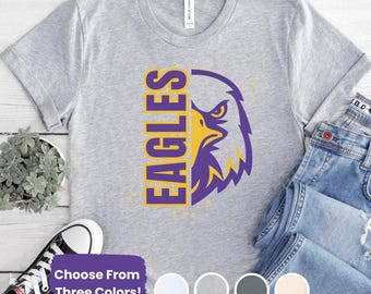 Puede incluir: Camiseta gris claro con un diseño de águila amarilla y morada y la palabra "EAGLES". La camiseta también tiene el texto "Choose From Three Colors!" y una selección de opciones de color.