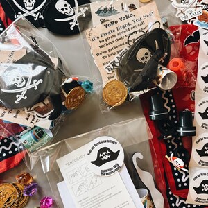 May include: A collection of pirate-themed party favors including black felt eye patches with white skull and crossbones, gold plastic coins, temporary tattoos with instructions, stickers reading Dead Men Tell No Tales, and red bandanas with white patterns.