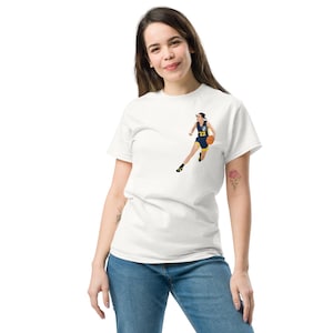 May include: White t-shirt featuring a graphic of a basketball player dribbling the ball. The player is wearing a blue and yellow jersey with the number 22 on it.