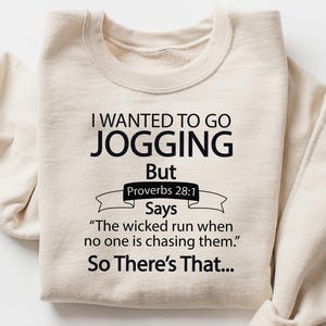 May include: Beige sweatshirt with the text "I WANTED TO GO JOGGING But Proverbs 28:1 Says 'The wicked run when no one is chasing them.' So There's That..." in black. The sweatshirt has long sleeves.