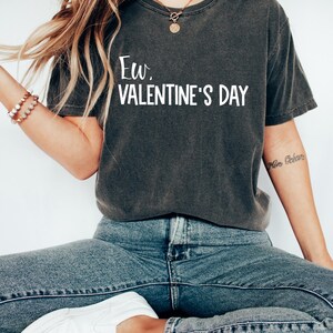 May include: A dark grey t-shirt with the text "Ew. Valentine's Day" printed in white.