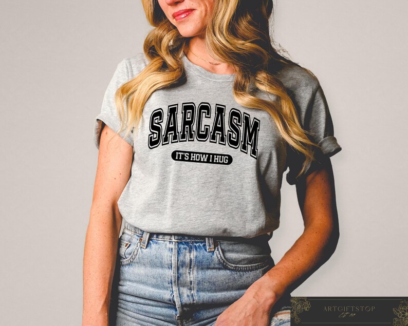 May include: A gray t-shirt with black text that reads "Sarcasm It's How I Hug".