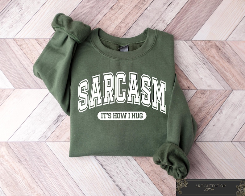 May include: A green sweatshirt with white text that reads "SARCASM IT'S HOW I HUG".