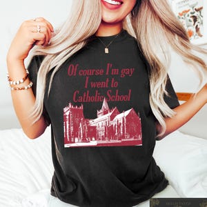 May include: Black t-shirt with a red graphic print of a church and the text "Of course I'm gay I went to Catholic School."