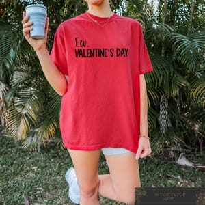 May include: Red oversized t-shirt with the text "Ew, Valentine's Day" printed in black.