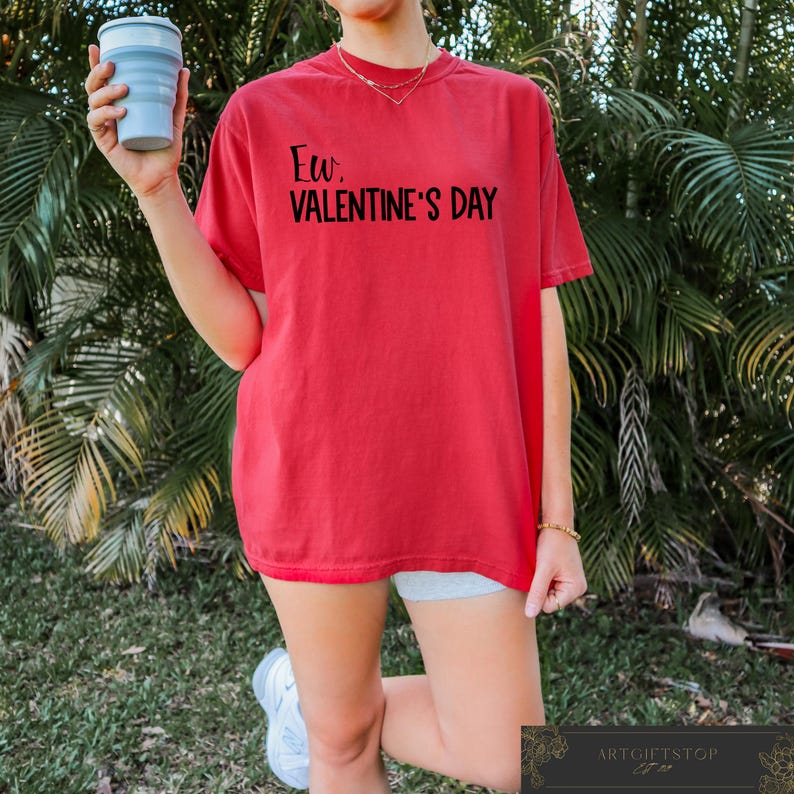 May include: Red oversized t-shirt with the text "Ew, Valentine's Day" printed in black.