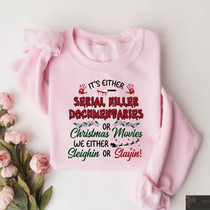 May include: Pink sweatshirt with a Christmas-themed graphic that says "It's either Serial Killer Documentaries or Christmas Movies. We either Sleighin or Slayin!"