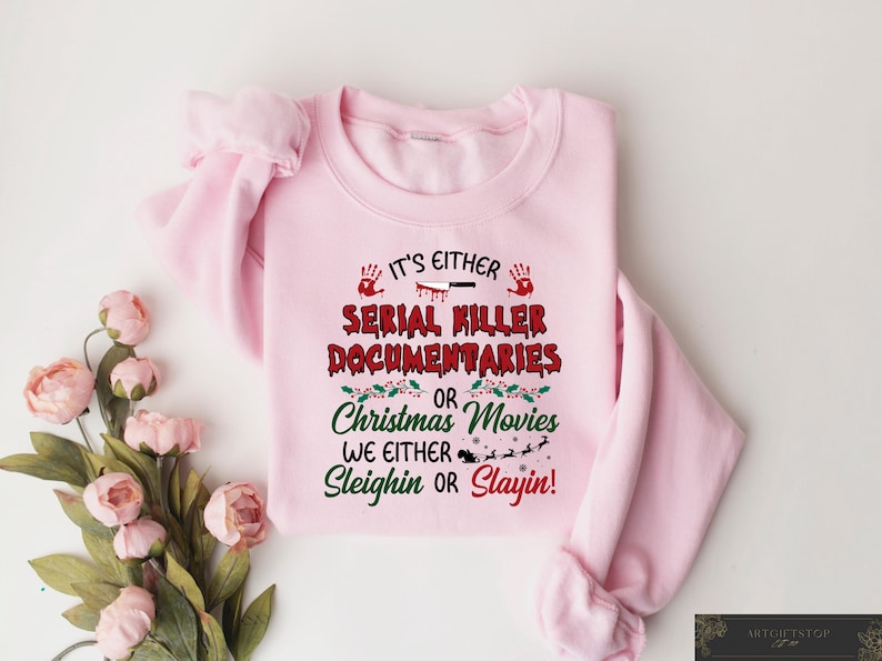 May include: Pink sweatshirt with a Christmas-themed graphic that says "It's either Serial Killer Documentaries or Christmas Movies. We either Sleighin or Slayin!"