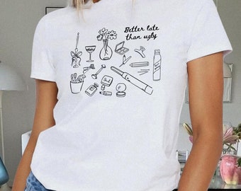 Könnte beinhalten: Weißes T-Shirt mit einer schwarzen Grafik verschiedener Beauty- und Modeartikel. Der Text "Better late than ugly" ist auf das Shirt gedruckt.