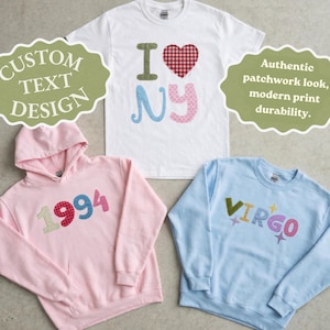 Op de afbeelding: Een wit t-shirt met "I NY" patchwork design, een roze hoodie met "1994" patchwork en een lichtblauwe sweatshirt met "VIRGO" patchwork. De afbeelding bevat ook de tekst "Custom Text Design" en "Authentic patchwork look, modern print durability."