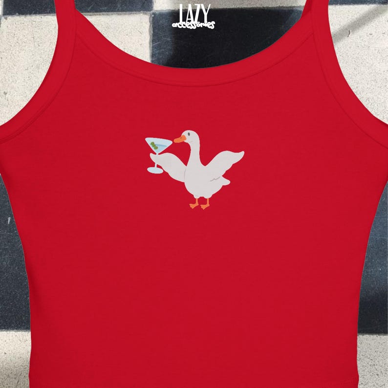Puede incluir: Camiseta de tirantes roja con un ganso blanco sosteniendo una copa de martini. El ganso lleva una pajarita azul. La camiseta tiene el texto "LAZY accessories" en la parte superior.