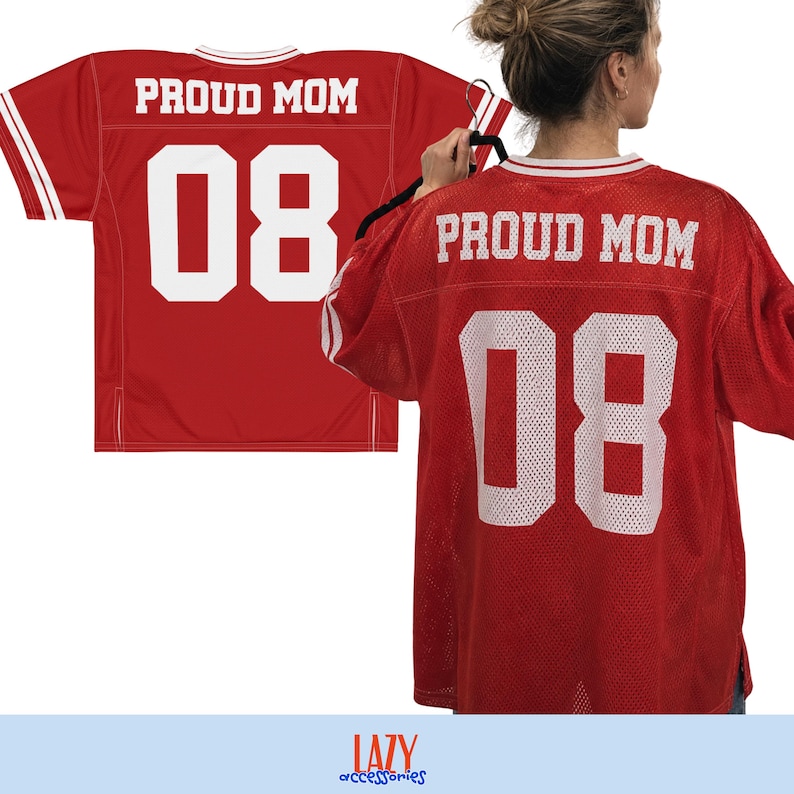 May include: A red mesh jersey featuring white text that reads PROUD MOM and the number 08 in a bold athletic font. The garment has white striped detailing on the sleeves and collar, presented in both a flat view and a worn view.