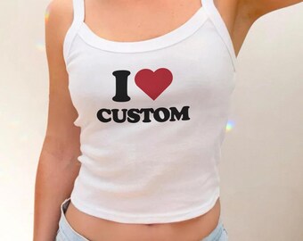 May include: White tank top with the text "I ♥ CUSTOM" in black and red. The top has a scoop neckline and thin straps. The tank top is made of a soft, ribbed material.