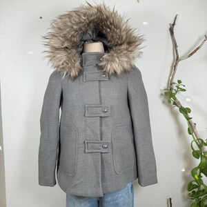 May include: A gray hooded coat with a faux fur trim around the hood. The coat has a button closure and two pockets.