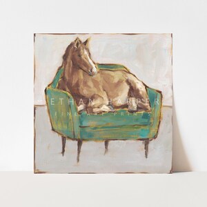 May include: A painting of a brown horse lying on a teal green velvet armchair with gold accents. The background is a light beige color.