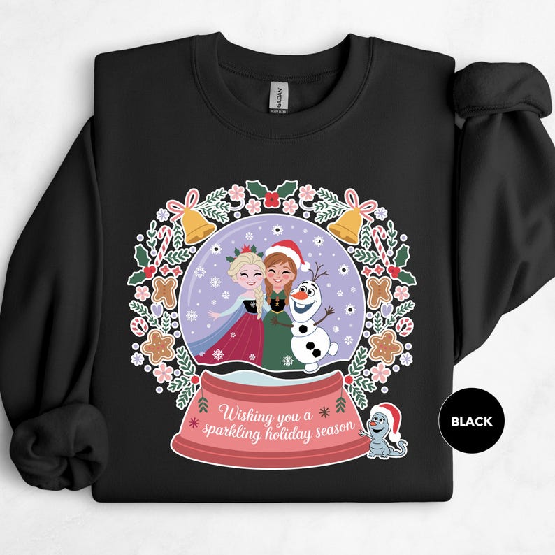 A black sweatshirt with a colorful illustration of two girls and a snowman on a Christmas-themed background.