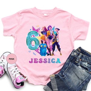 May include: A light pink t-shirt featuring a graphic design for a sixth birthday. The design includes a teal number 6, a blue cat, and the name "Jessica" in colorful letters. A pair of pink sneakers and blue jeans are also in the image.