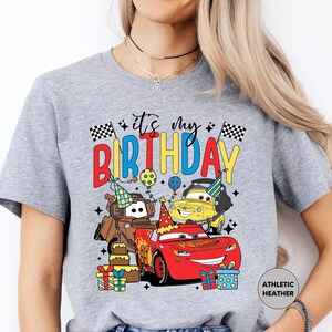a woman wearing a birthday t - shirt with cars on it