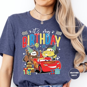 a woman wearing a birthday shirt with cars on it