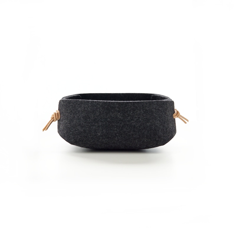 Side view of small wool charcoal felt catch all with leather toggles in natural light tan. Great as night stand tray.