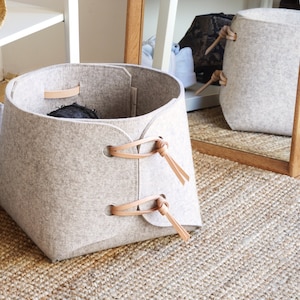 Light grey felt storage bin with leather details standing on floor from Skandinavious By Louise Vilmar