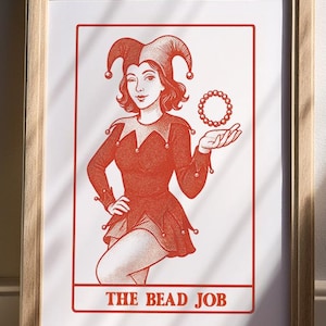 Könnte beinhalten: Gerahmter Druck mit einer rot-weißen Illustration eines Narren, der einen Perlenkreis hält. Der Narr trägt ein rotes Kostüm und einen Hut mit Schellen. Der Text "THE BEAD JOB" steht unten. Holzrahmen.